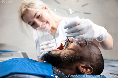 Image of Young african-american man visiting dentist\'s office