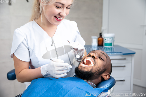 Image of Young african-american man visiting dentist\'s office