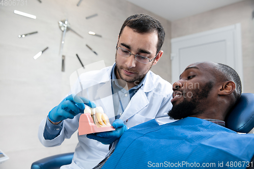 Image of Young african-american man visiting dentist\'s office