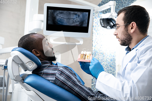 Image of Young african-american man visiting dentist\'s office, using technologies