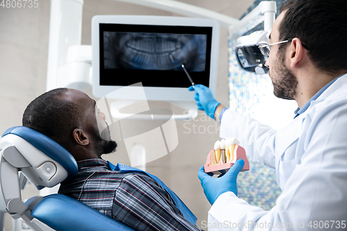 Image of Young african-american man visiting dentist\'s office, using technologies