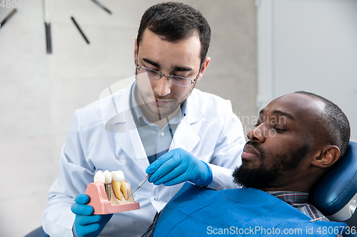 Image of Young african-american man visiting dentist\'s office