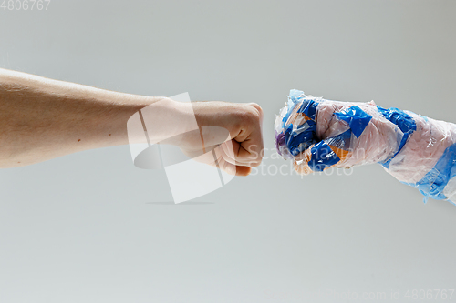 Image of Big plastic hand made of garbage shaking another hand isolated on white studio background