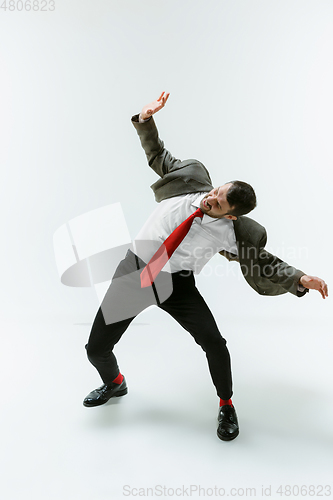 Image of Young caucasian man moving flexible on white studio background