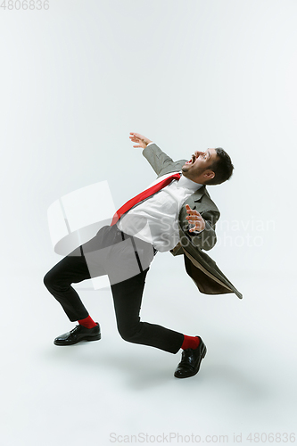 Image of Young caucasian man moving flexible on white studio background