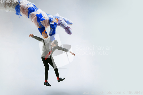 Image of Young caucasian man avoiding big plastic hand on white studio background