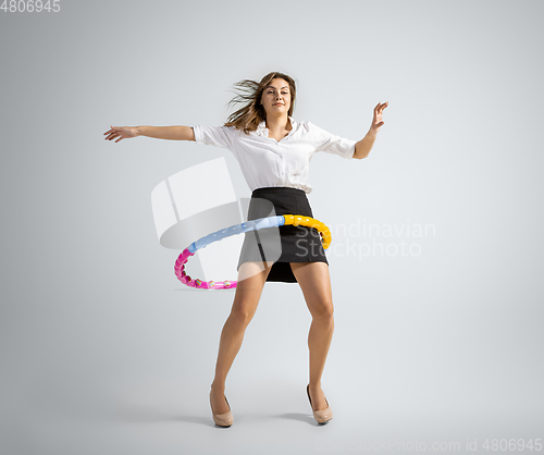 Image of Caucasian woman in office clothes training with hoop isolated on grey studio background