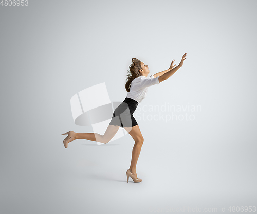 Image of Caucasian woman in office clothes running isolated on grey studio background