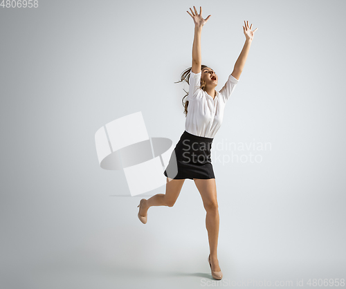 Image of Caucasian woman in office clothes catching ball isolated on grey studio background