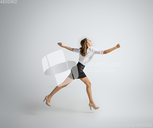 Image of Caucasian woman in office clothes running isolated on grey studio background