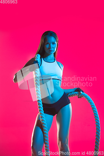 Image of Muscular young female athlete on pink background