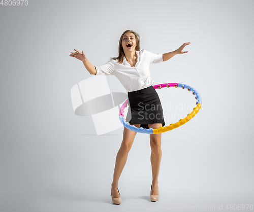 Image of Caucasian woman in office clothes training with hoop isolated on grey studio background