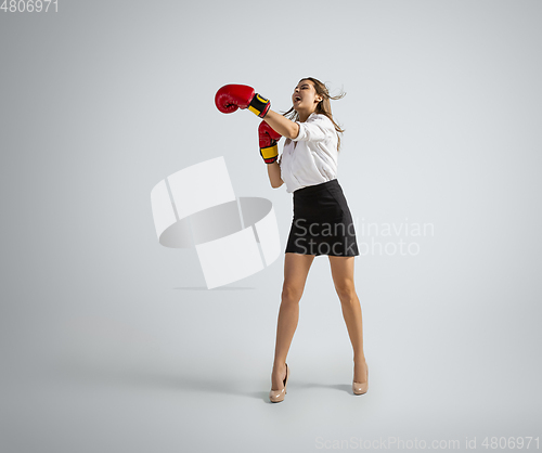 Image of Caucasian woman in office clothes boxing isolated on grey studio background