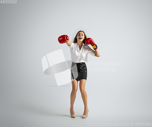 Image of Caucasian woman in office clothes boxing isolated on grey studio background