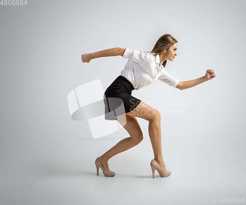 Image of Caucasian woman in office clothes preparing to run isolated on grey studio background