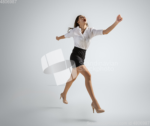 Image of Caucasian woman in office clothes running isolated on grey studio background