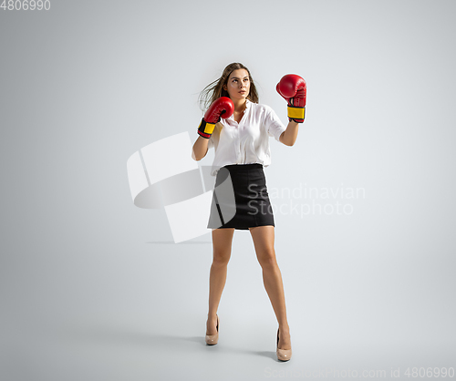 Image of Caucasian woman in office clothes boxing isolated on grey studio background