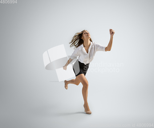 Image of Caucasian woman in office clothes running isolated on grey studio background