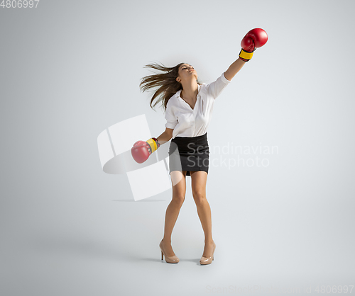 Image of Caucasian woman in office clothes boxing isolated on grey studio background