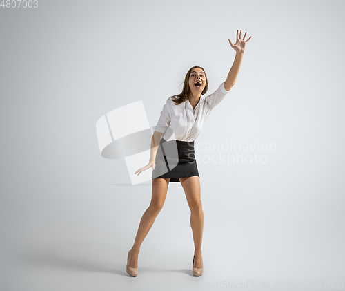 Image of Caucasian woman in office clothes catching ball isolated on grey studio background