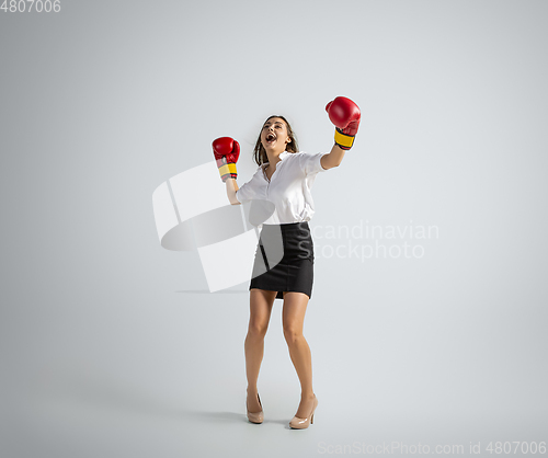 Image of Caucasian woman in office clothes boxing isolated on grey studio background