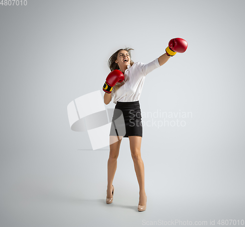 Image of Caucasian woman in office clothes boxing isolated on grey studio background