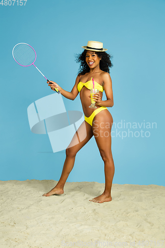 Image of Happy young woman resting on blue studio background