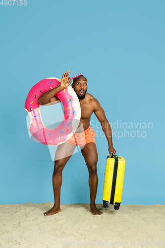 Image of Happy young man resting on blue studio background