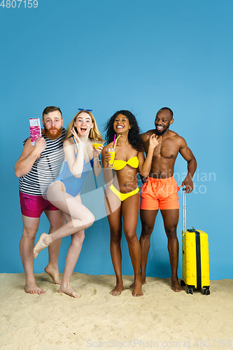 Image of Happy young friends resting on blue studio background