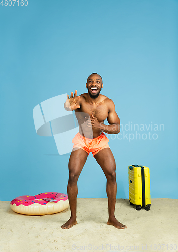 Image of Happy young man resting on blue studio background