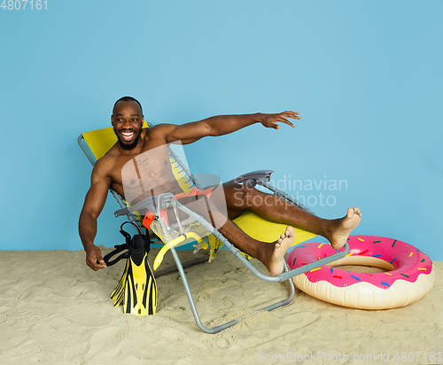 Image of Happy young man resting on blue studio background