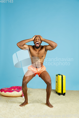 Image of Happy young man resting on blue studio background