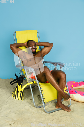 Image of Happy young man resting on blue studio background