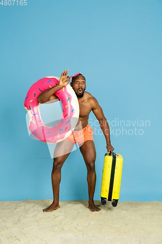 Image of Happy young man resting on blue studio background
