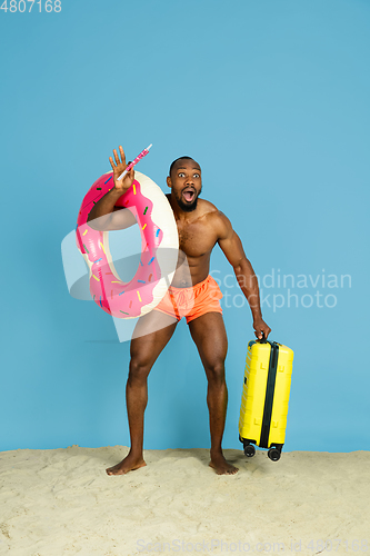Image of Happy young man resting on blue studio background