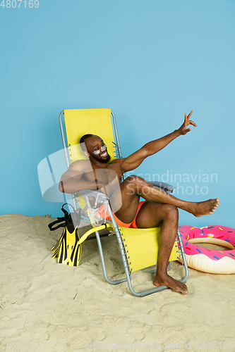 Image of Happy young man resting on blue studio background