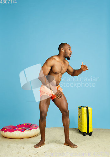Image of Happy young man resting on blue studio background