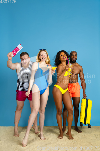 Image of Happy young friends resting on blue studio background