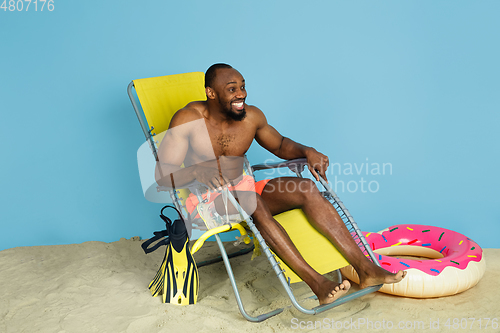 Image of Happy young man resting on blue studio background