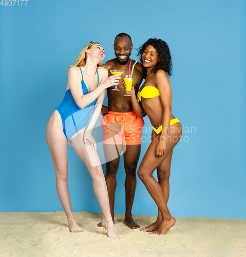 Image of Happy young friends resting on blue studio background