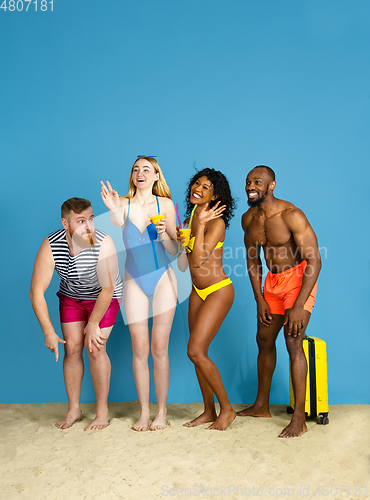 Image of Happy young friends resting on blue studio background