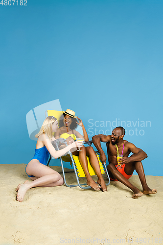 Image of Happy young friends resting on blue studio background