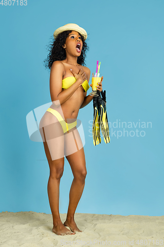 Image of Happy young woman resting on blue studio background