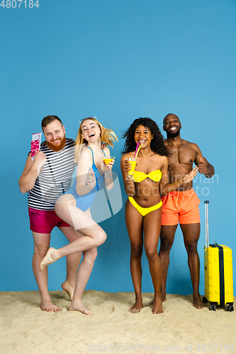 Image of Happy young friends resting on blue studio background