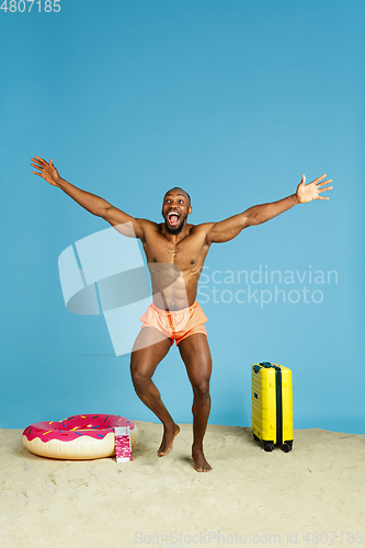 Image of Happy young man resting on blue studio background
