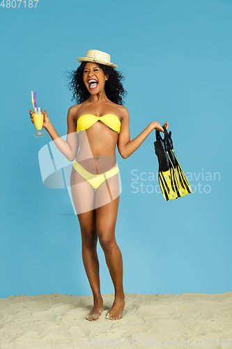 Image of Happy young woman resting on blue studio background