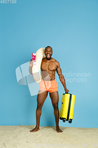 Image of Happy young man resting on blue studio background