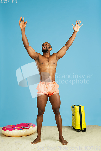 Image of Happy young man resting on blue studio background