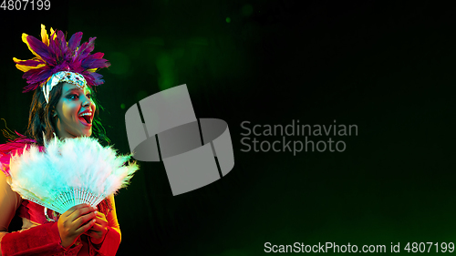 Image of Beautiful young woman in carnival mask and masquerade costume in colorful lights, flyer