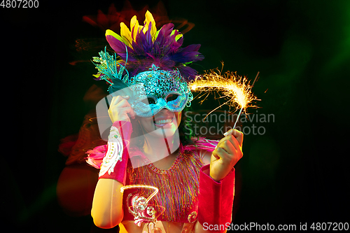 Image of Beautiful young woman in carnival mask and masquerade costume in colorful lights